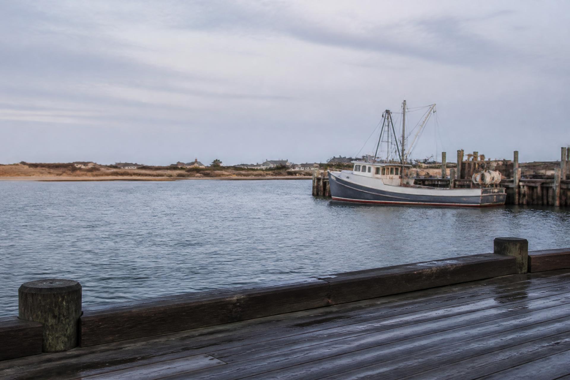 A working fishing boat moored along a quiet Long Island waterfront